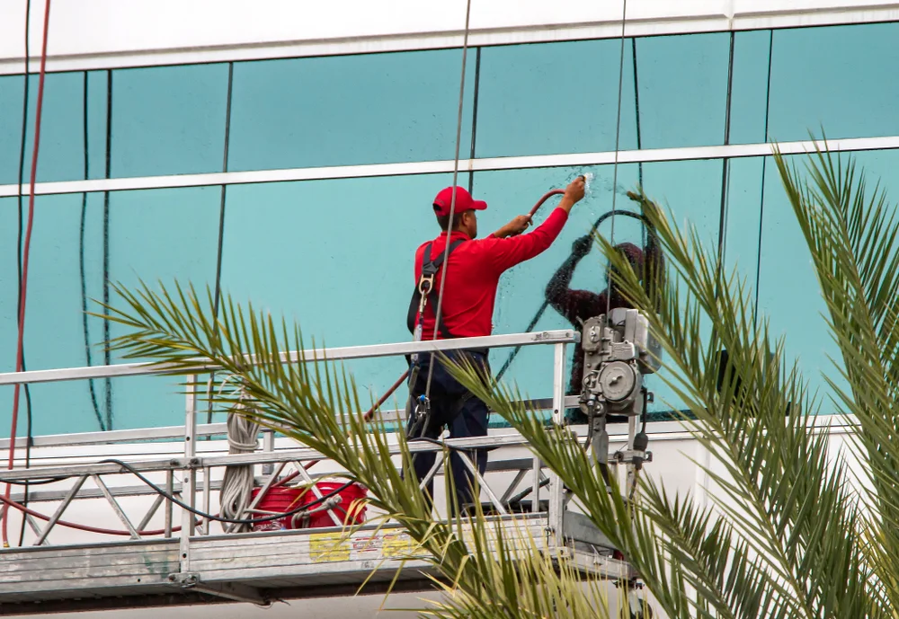 Professional installer working on large exterior glass windows of a commercial building.