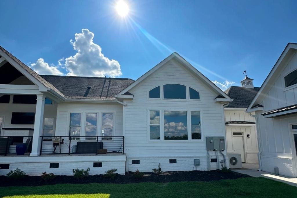 Modern white house with reflective residential window tint under bright sunlight