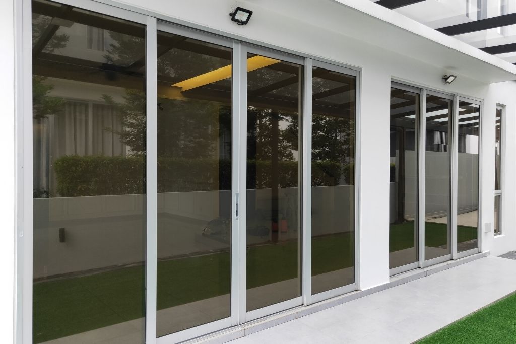 Modern home with large sliding glass doors featuring tinted security window film for privacy and protection.