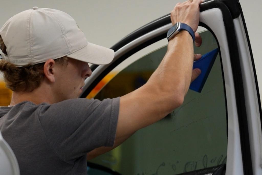 Technician applying ceramic window tint to a vehicle side window during installation