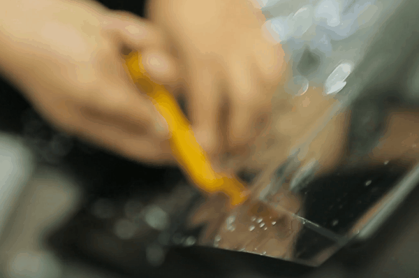 Close-up of technician trimming car window tint film with a precision cutting tool