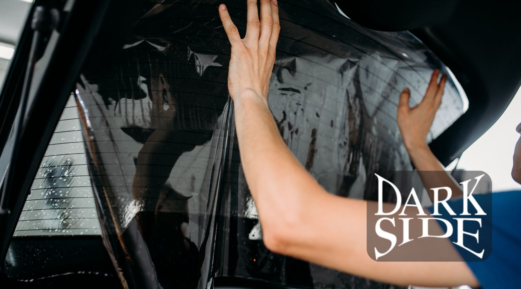 Dark Side Window Tinting technician applying automotive window tint to a vehicle window in Augusta, GA.
