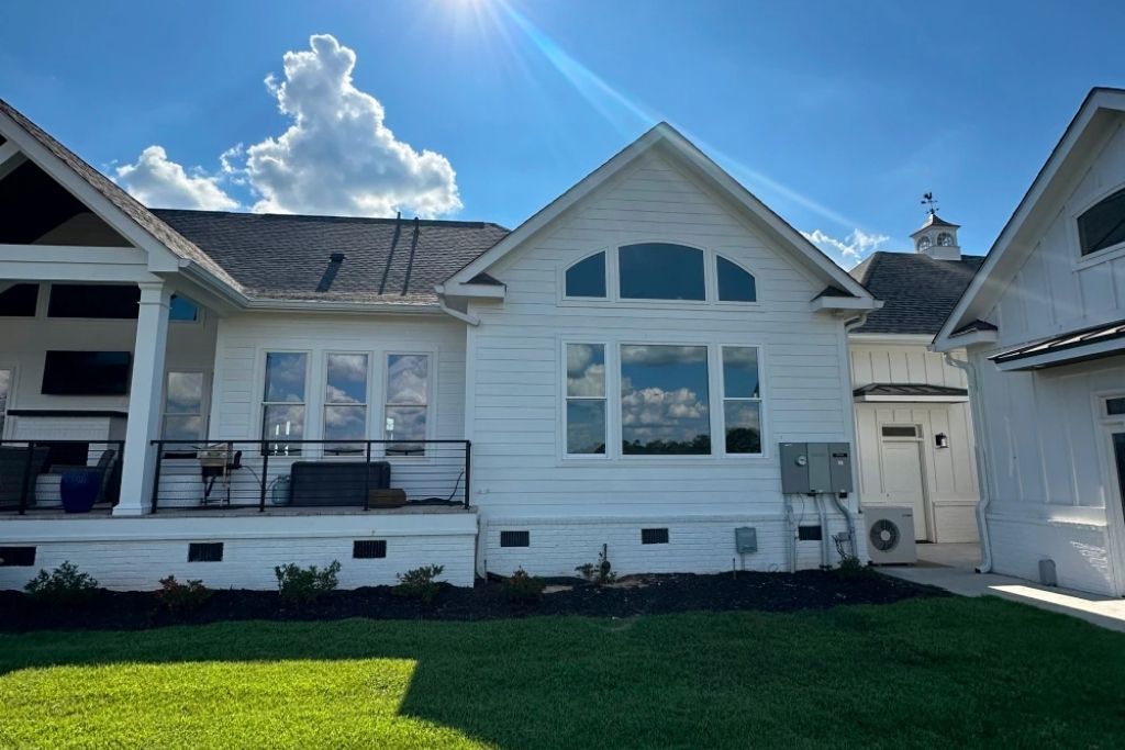 White Augusta home with professionally tinted residential windows reflecting the sky on a sunny day.