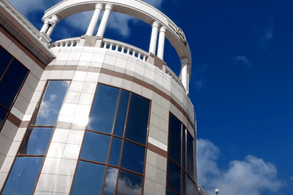Commercial building with large tinted glass windows reflecting the blue sky.