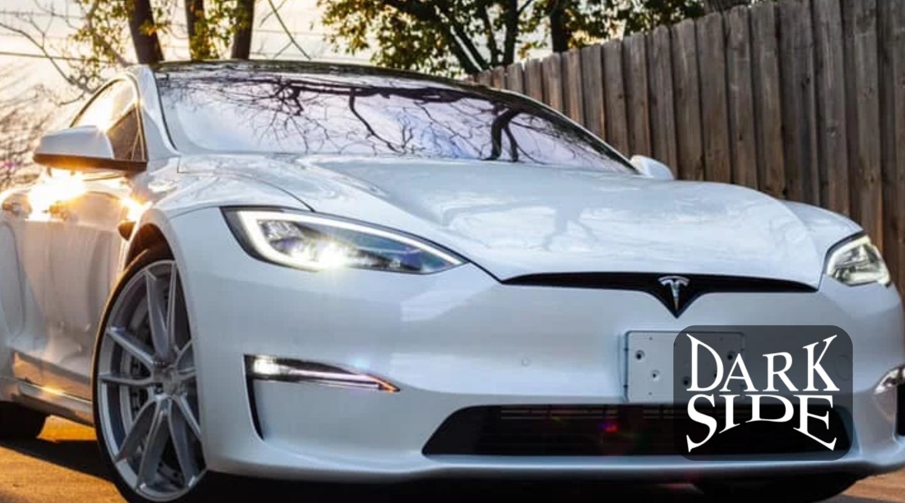 White Tesla with tinted windows parked outdoors in sunlight with Dark Side Window Tinting branding.
