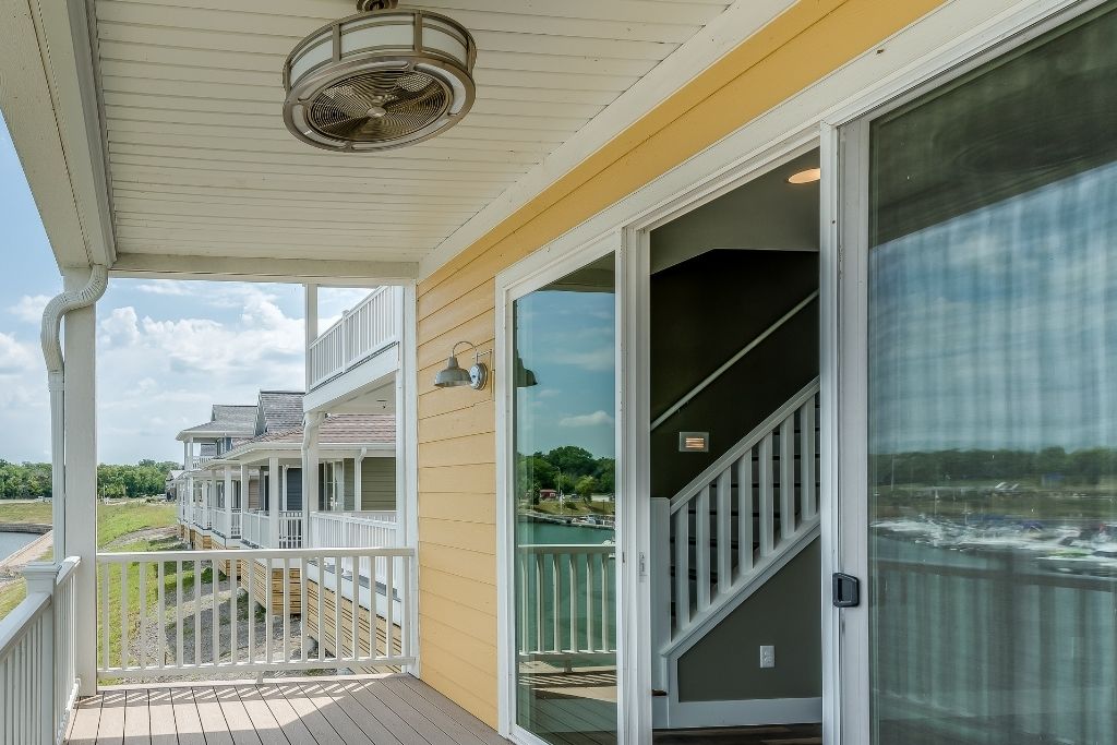 Covered porch with large sliding glass doors overlooking a waterfront residential community.