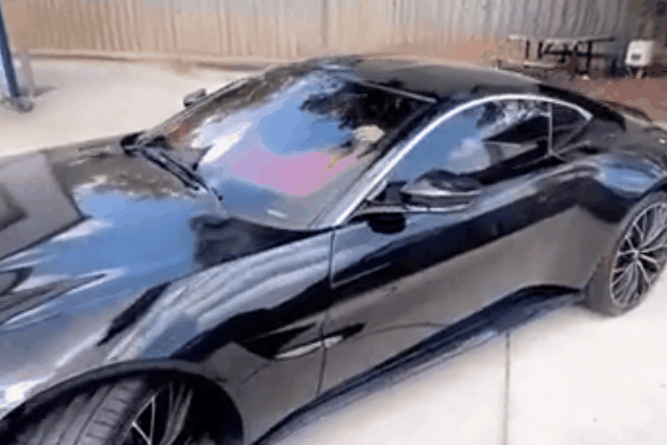 Black sports coupe with dark tinted windows parked inside an automotive tint shop.
