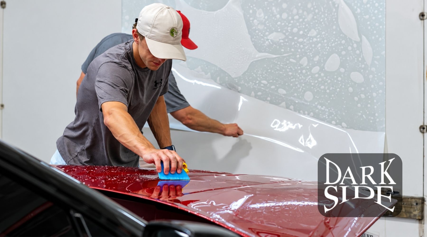 Technician applying paint protection film (PPF) to the hood of a red car at Dark Side Window Tinting in Augusta, GA.